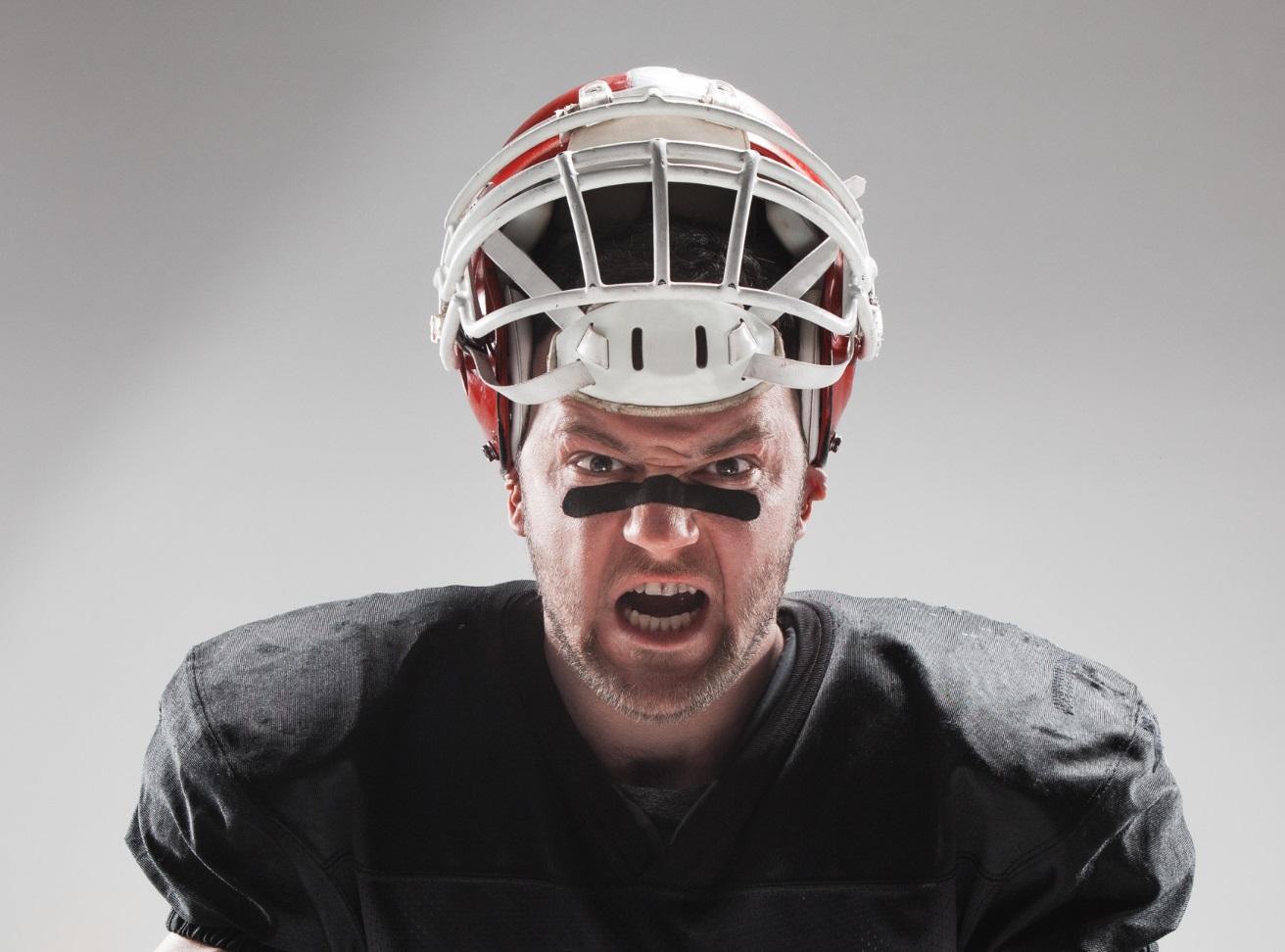 Man wearing football uniform and helmet on his head ,with angry face.