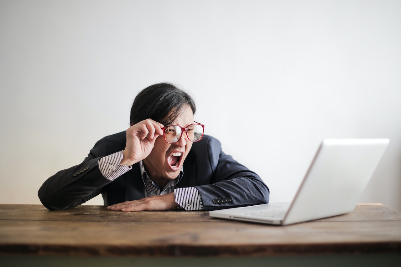 Young man is yelling and looking at laptop screen.