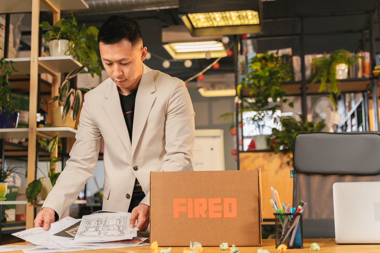 Young man is collecting his things from office desk ,being FIRED.