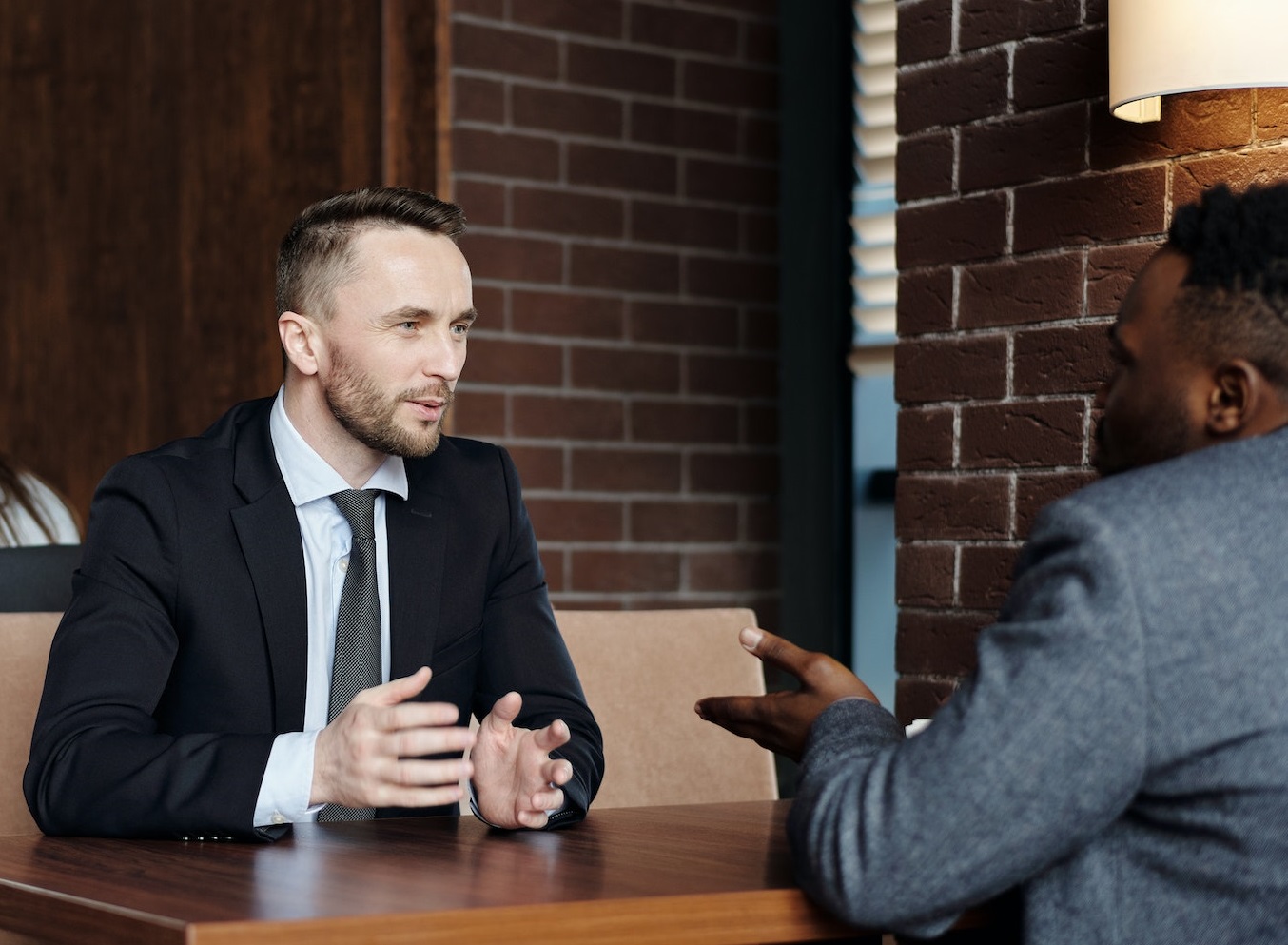 Two man are talking and seating at restaurant table.