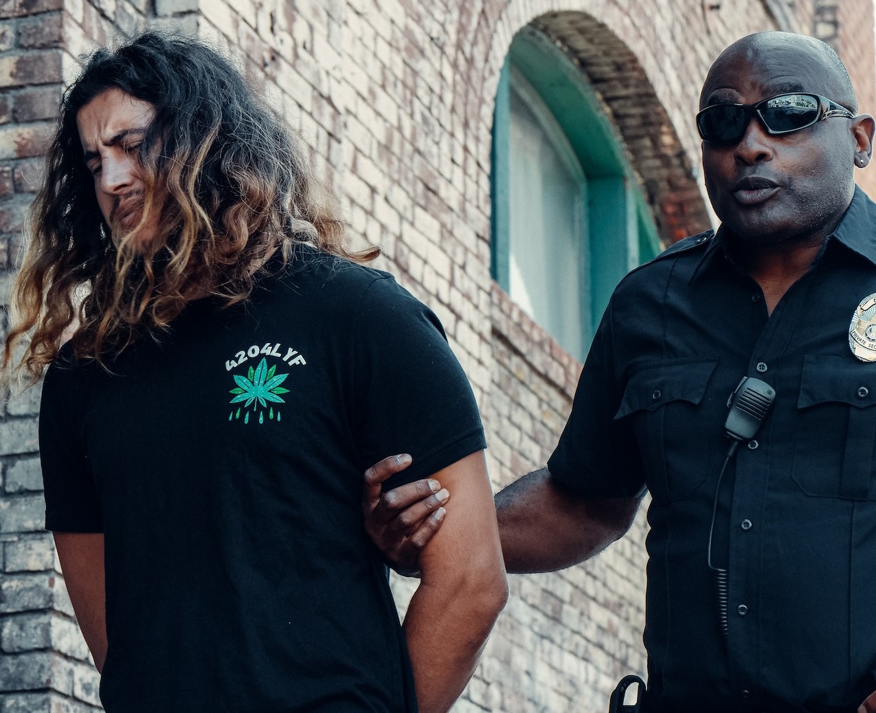 Policeman is holding the arms of arrested man.