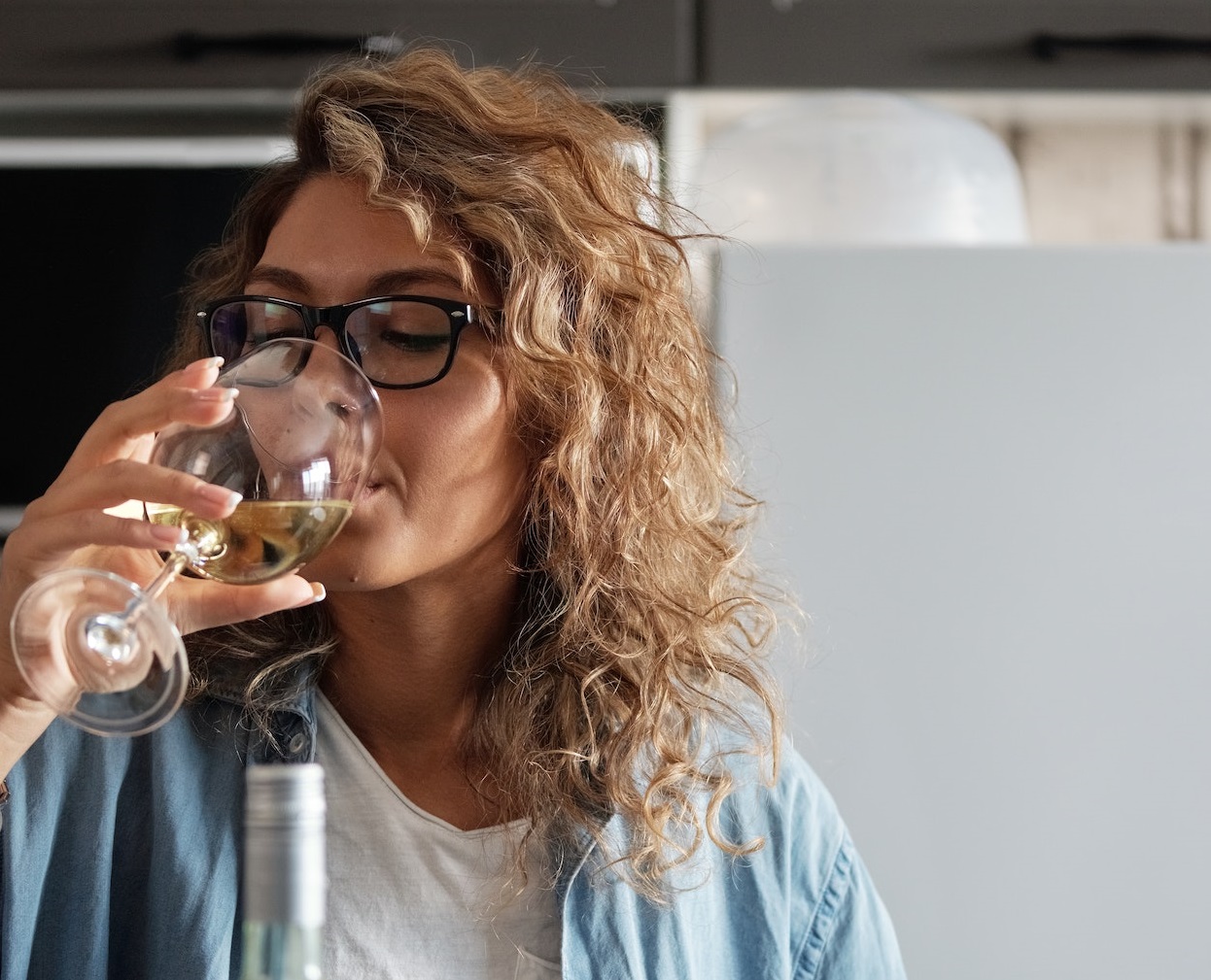 Woman with long hair is drinking white wine from a glass