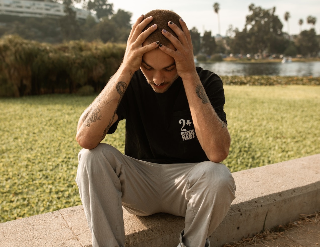 Young kid is seating on the ground ,holding his head with sad face.