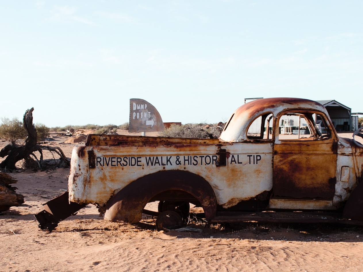 Old rusty car with missing parts is seating in desert.