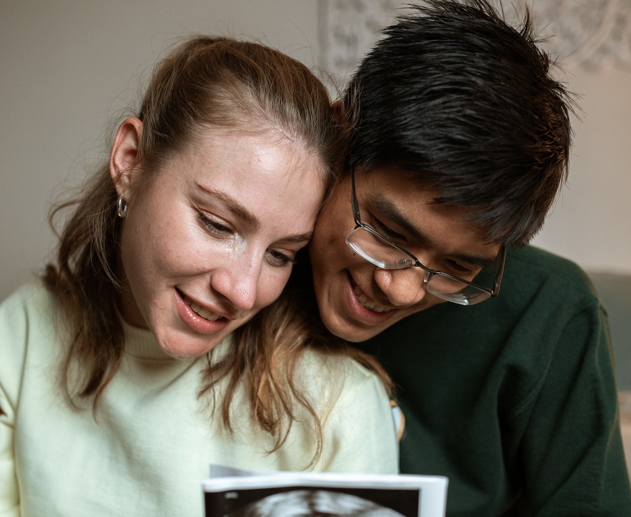 Young couple are looking a picture of baby ,smiling.