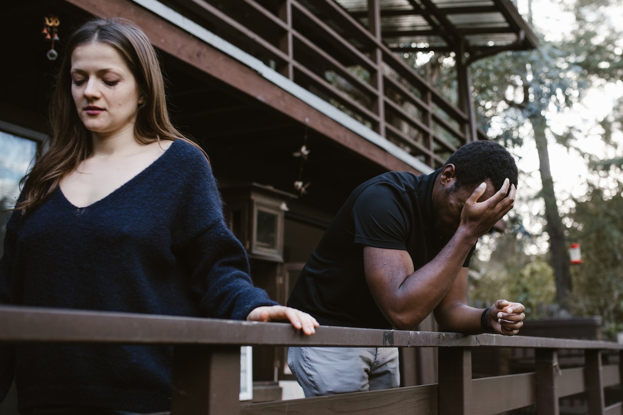 Man is crying next to a woman in black shirt looking down.
