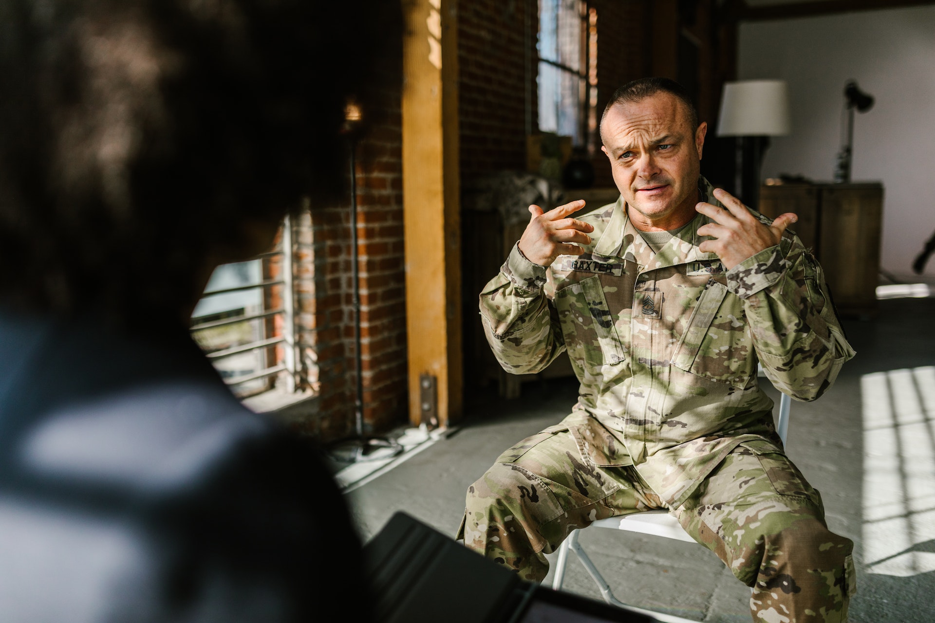 Man in military uniform is talking to another person in office.