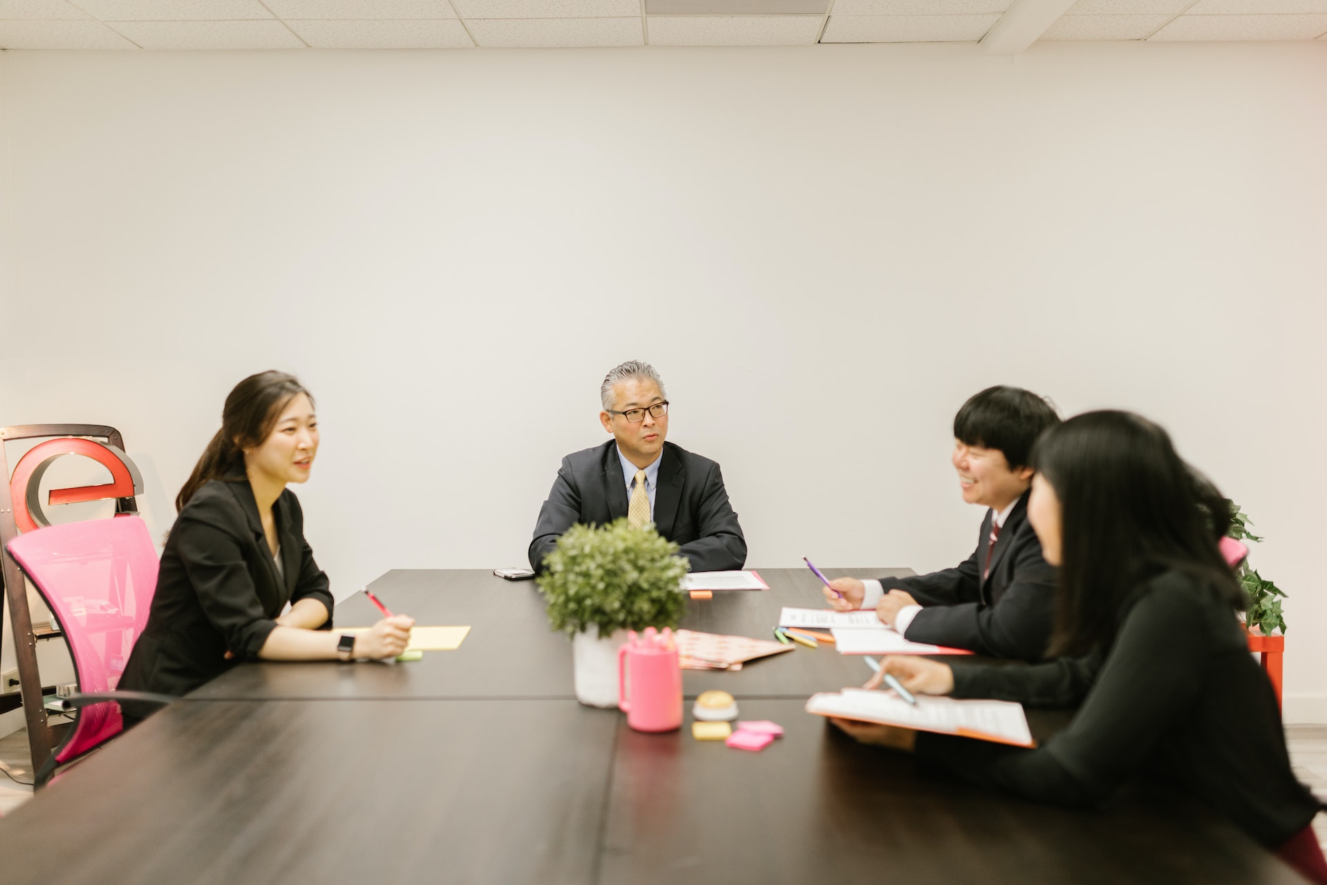 A group of people is having a company meeting in the office and smiling.