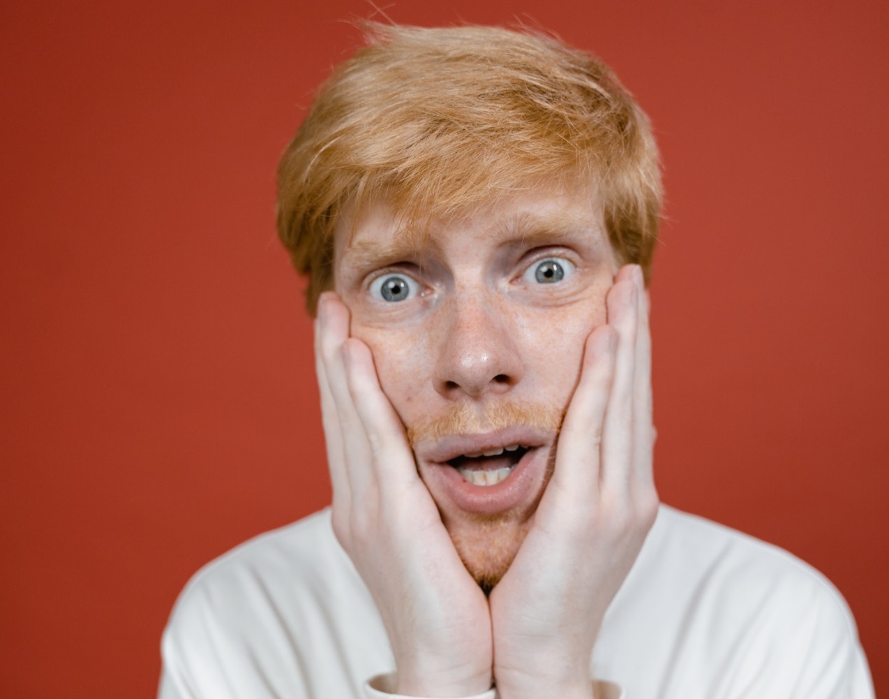 Young man with shocked face on red background.