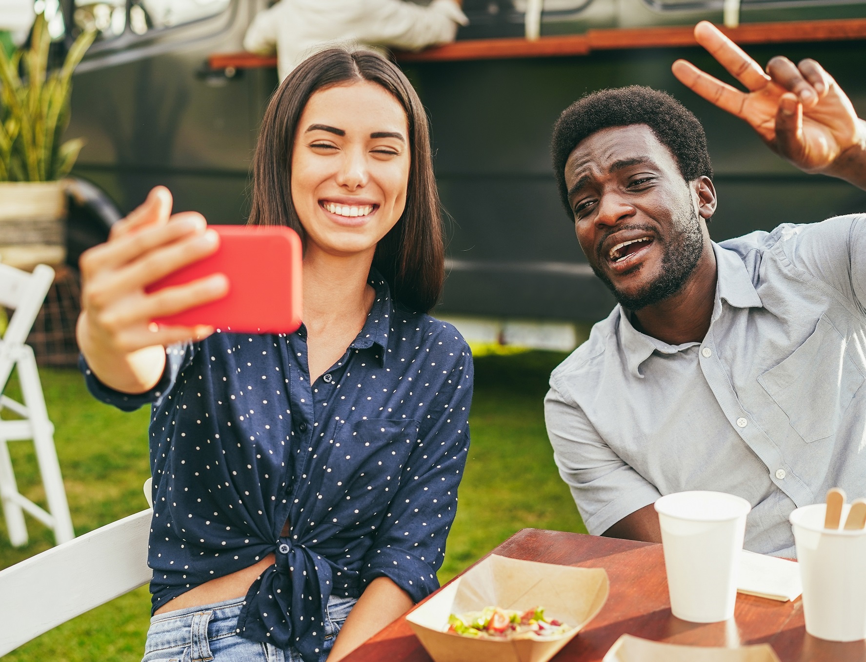People having fun doing selfie with mobile phone at food truck restaurant outdoor .