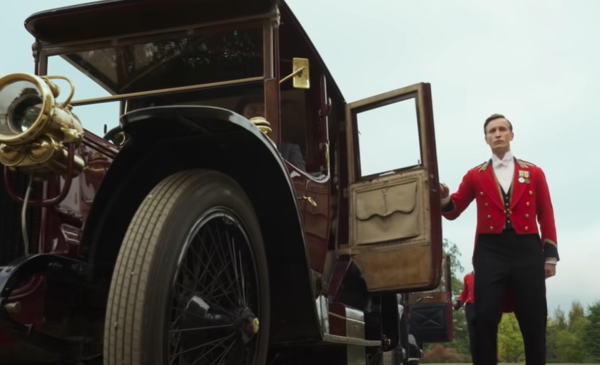 butler in red uniform opening car door