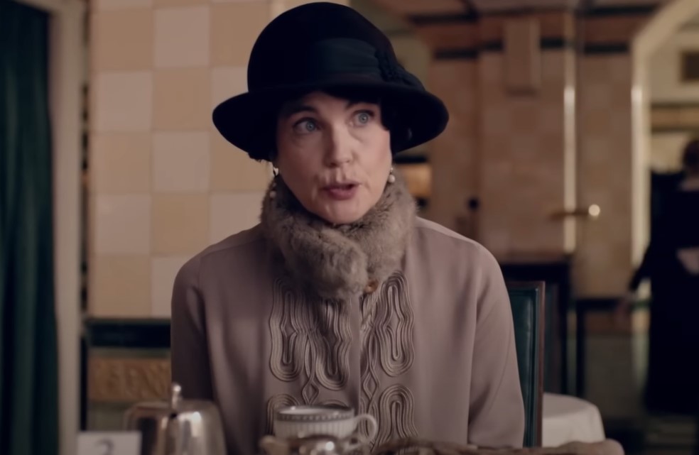 Downton Abbey Cora sitting in restaurant in coat