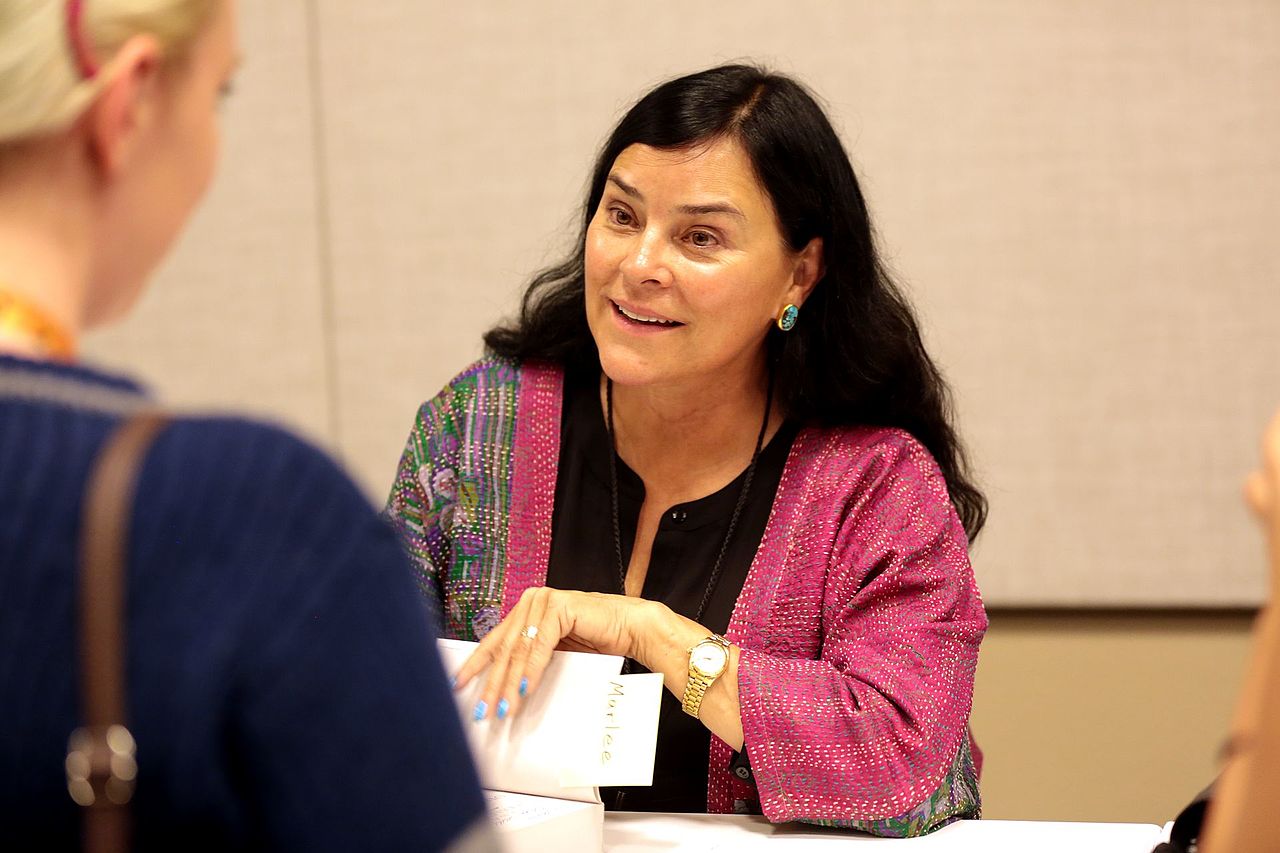 Diana Gabaldon wearing black shirt and pink jacket is signing books - 2017
