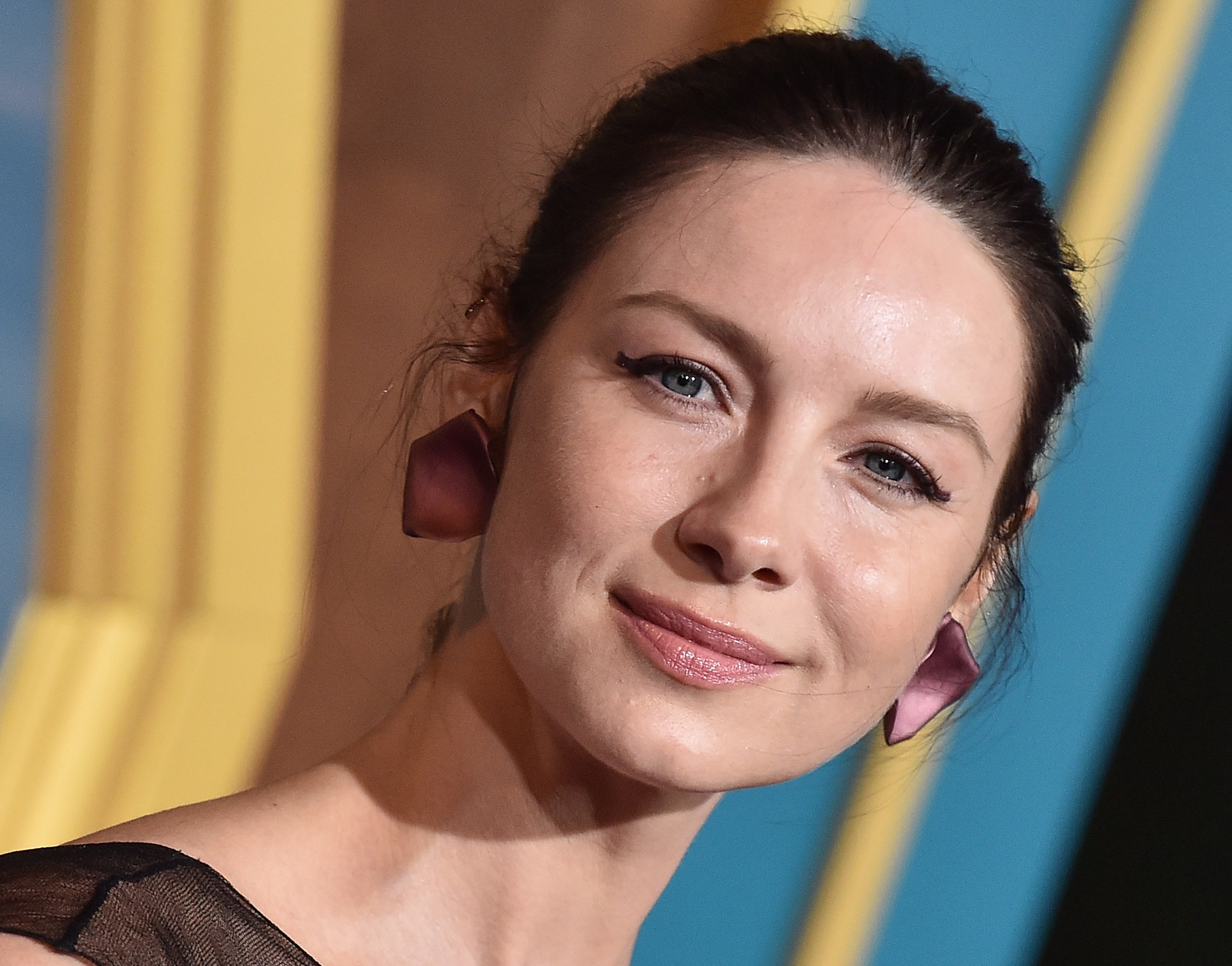 Caitriona Balfe wearing pink earrings is smiling and looking at camera - 2020