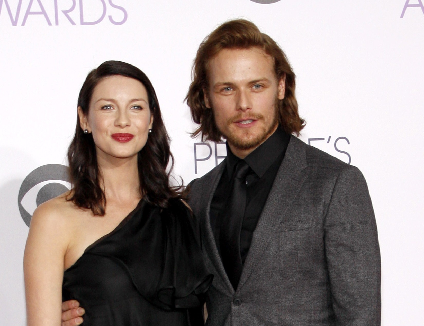 Sam Heughan and Caitriona Balfe standing and smiling at camera - 2015