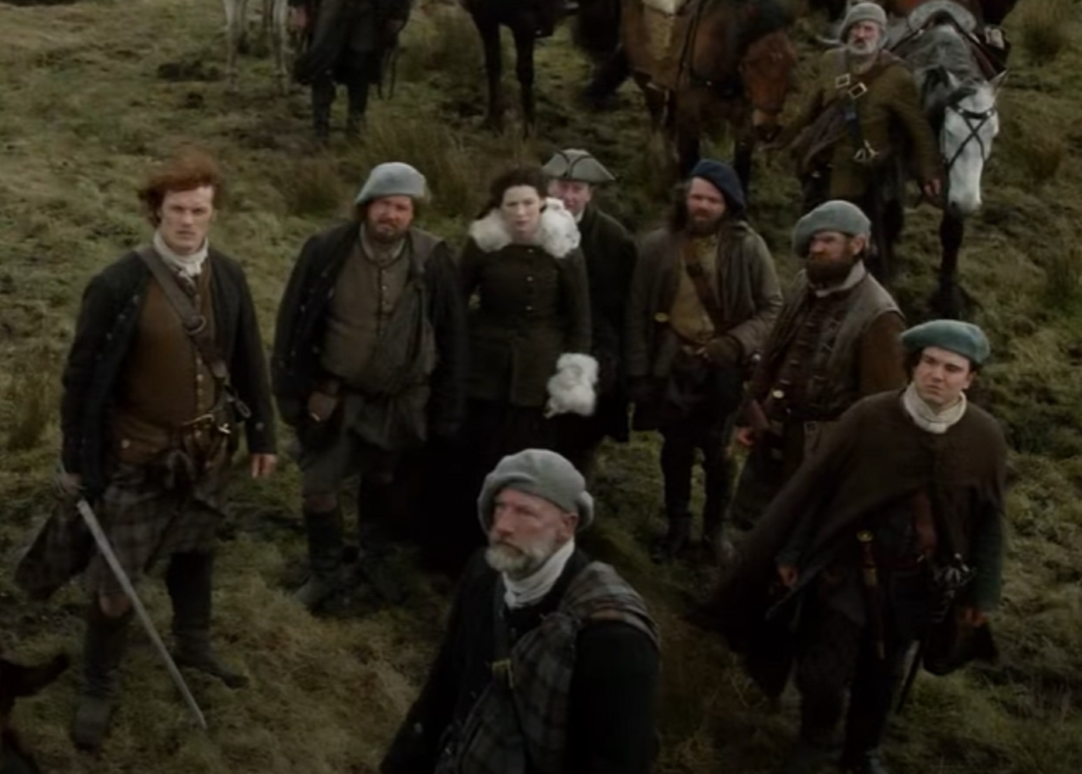 Screenshot: Actors wearing kilts outside and looking up - from Outlander (Tv Series)