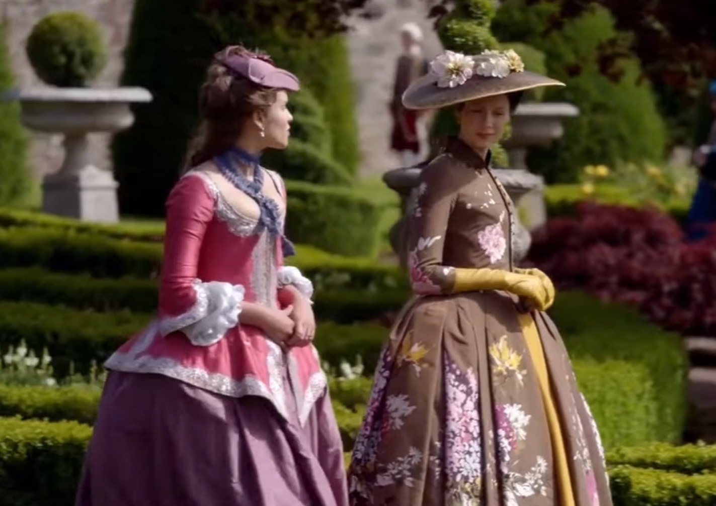 Screenshot: Claire Fraser wearing brown dress with flowers is walking outside - from Outlander (Tv Series)
