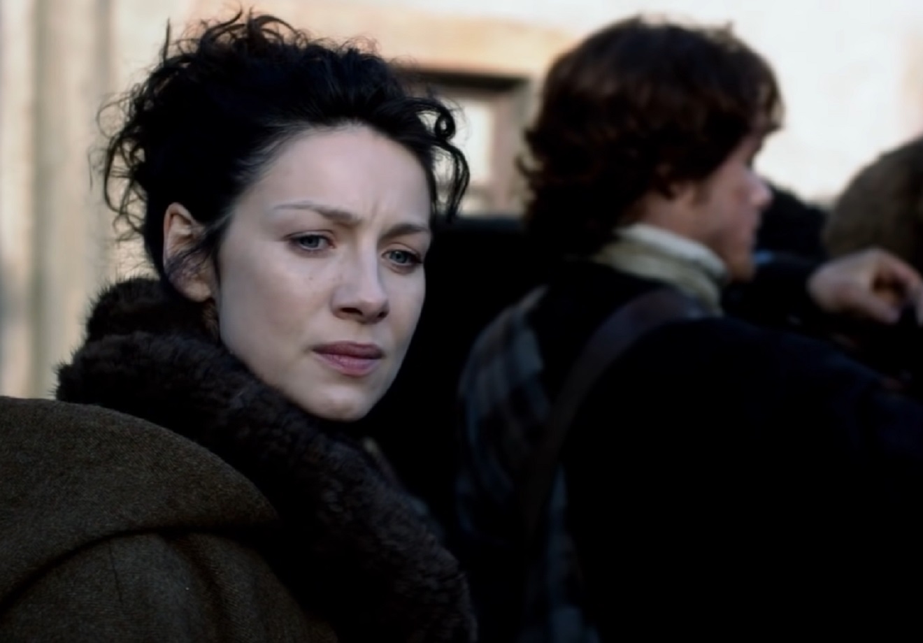 Screenshot: Claire Fraser (Caitríona Balfe) is standing outside ,looking upset - from Outlander (TV series)