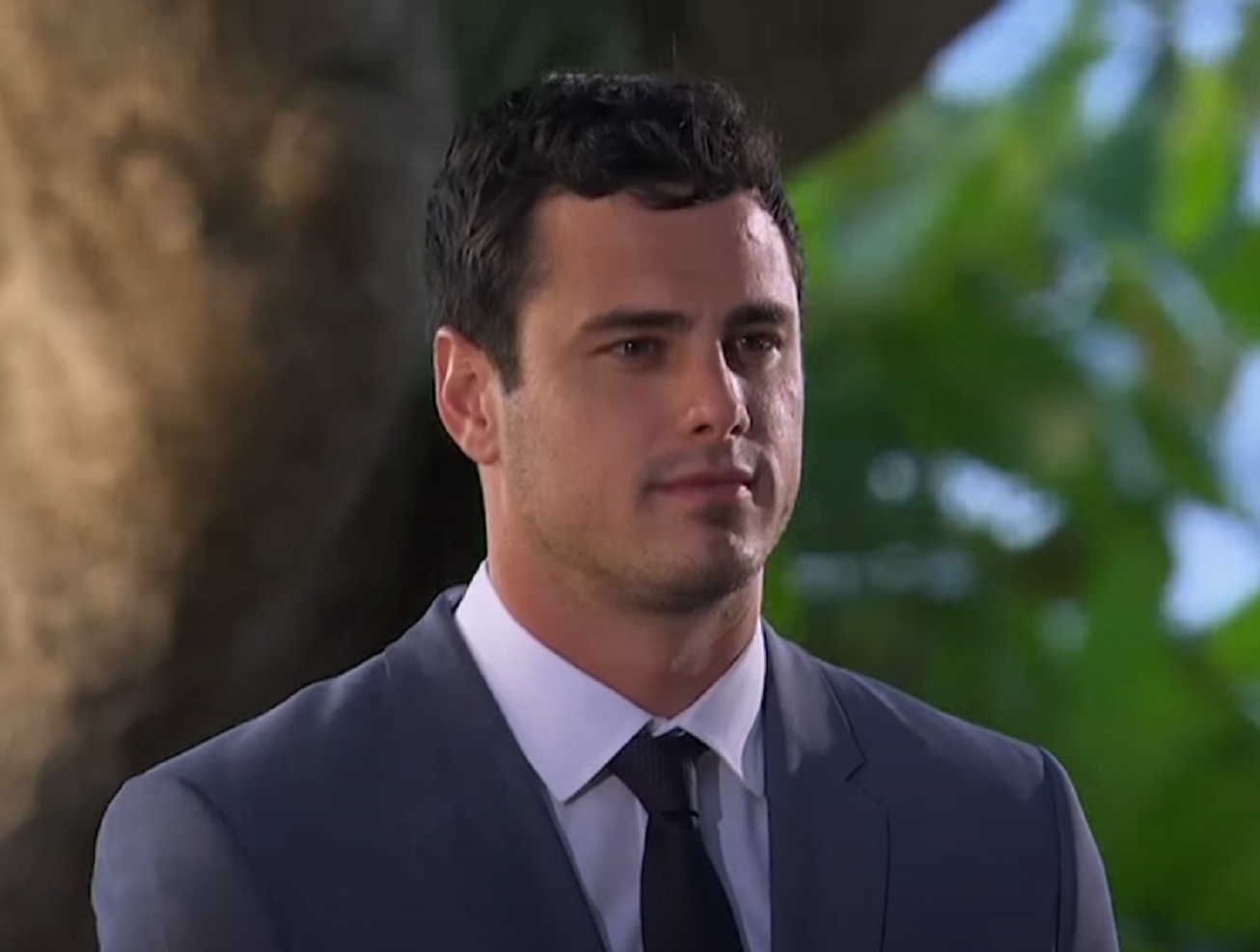 Screenshot: Ben Higgins wearing blue suit is looking at side - from The Bachelor (American TV series)