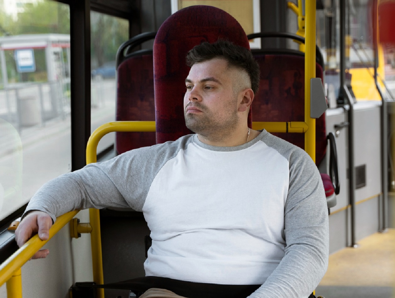 Young man wearing grey shirt is seating in the bus.
