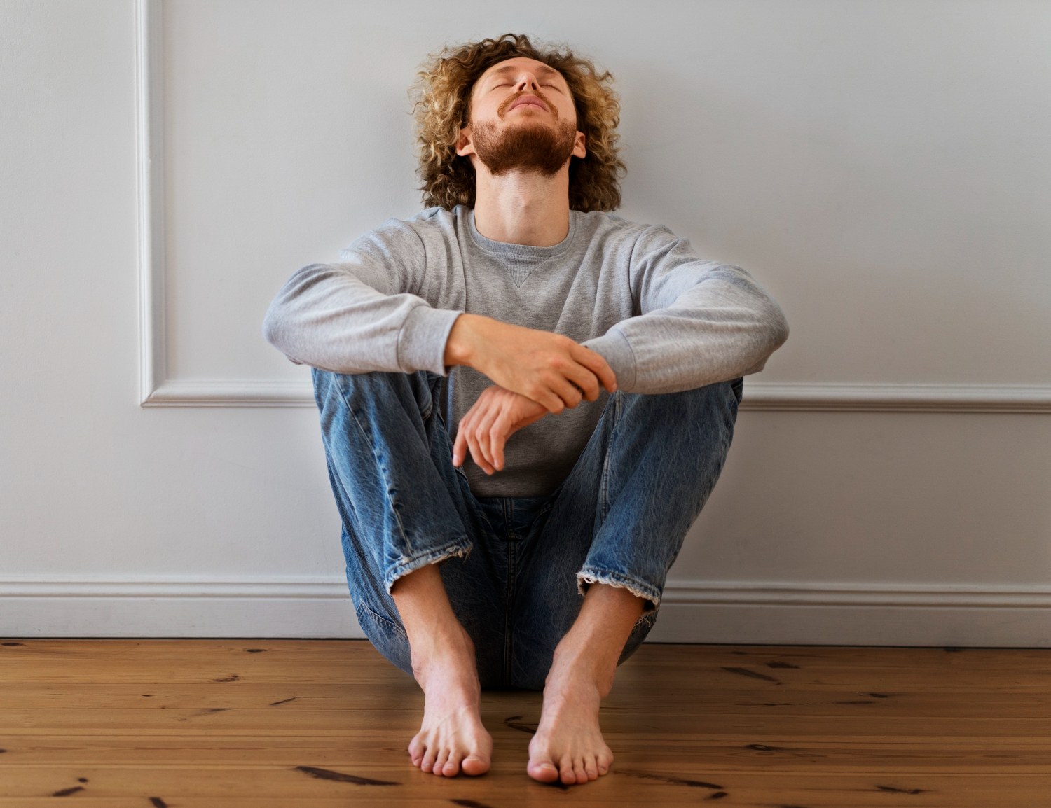 Young man is seating on the floor with naked feet.
