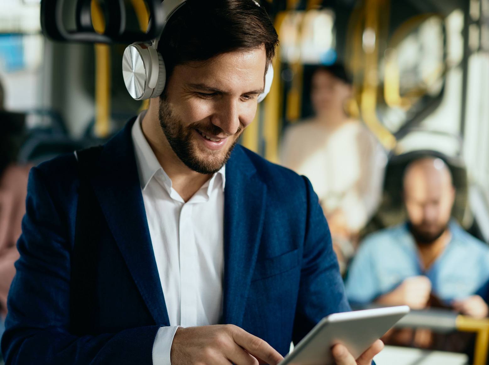 Man in blue suit is watching a movie on tablet in train.