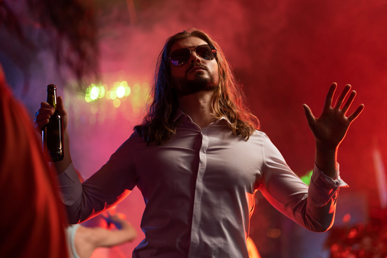 Man is holding a bottle and walking at party.