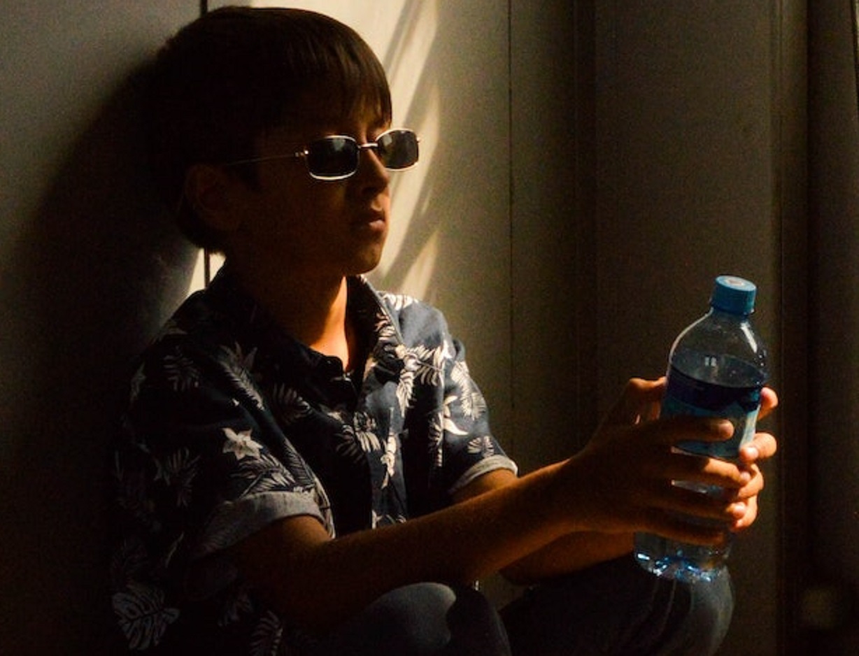 Man is holding a water bottle in dark room.