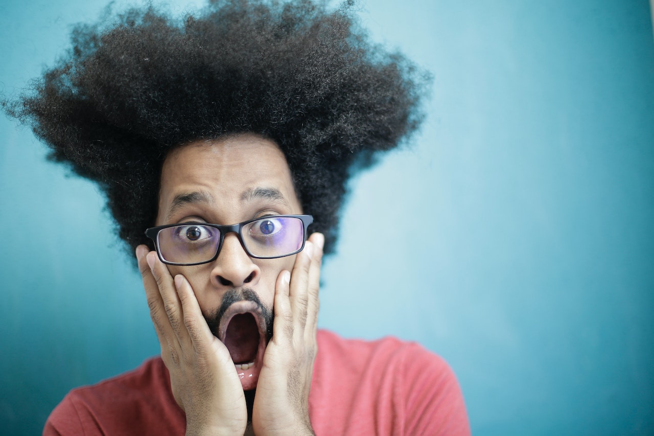 Man looking shocked wearing red shirt and glasses.