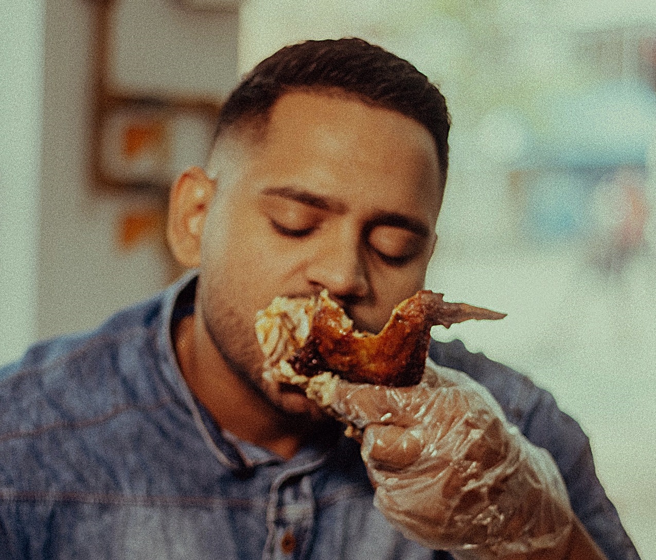 Man is looking and eating a roasted chicken.