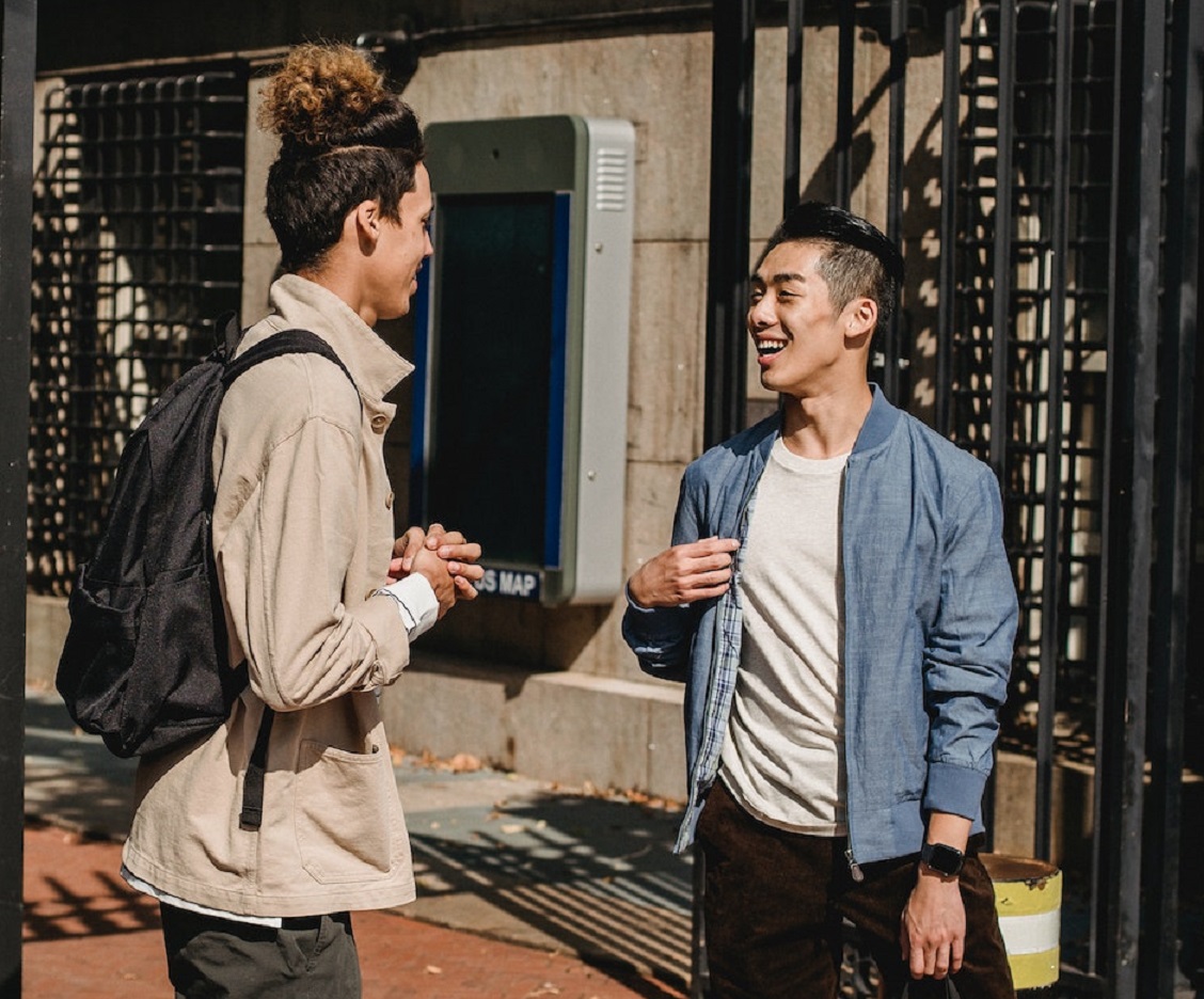 Two young man are talking and laughing on the street.
