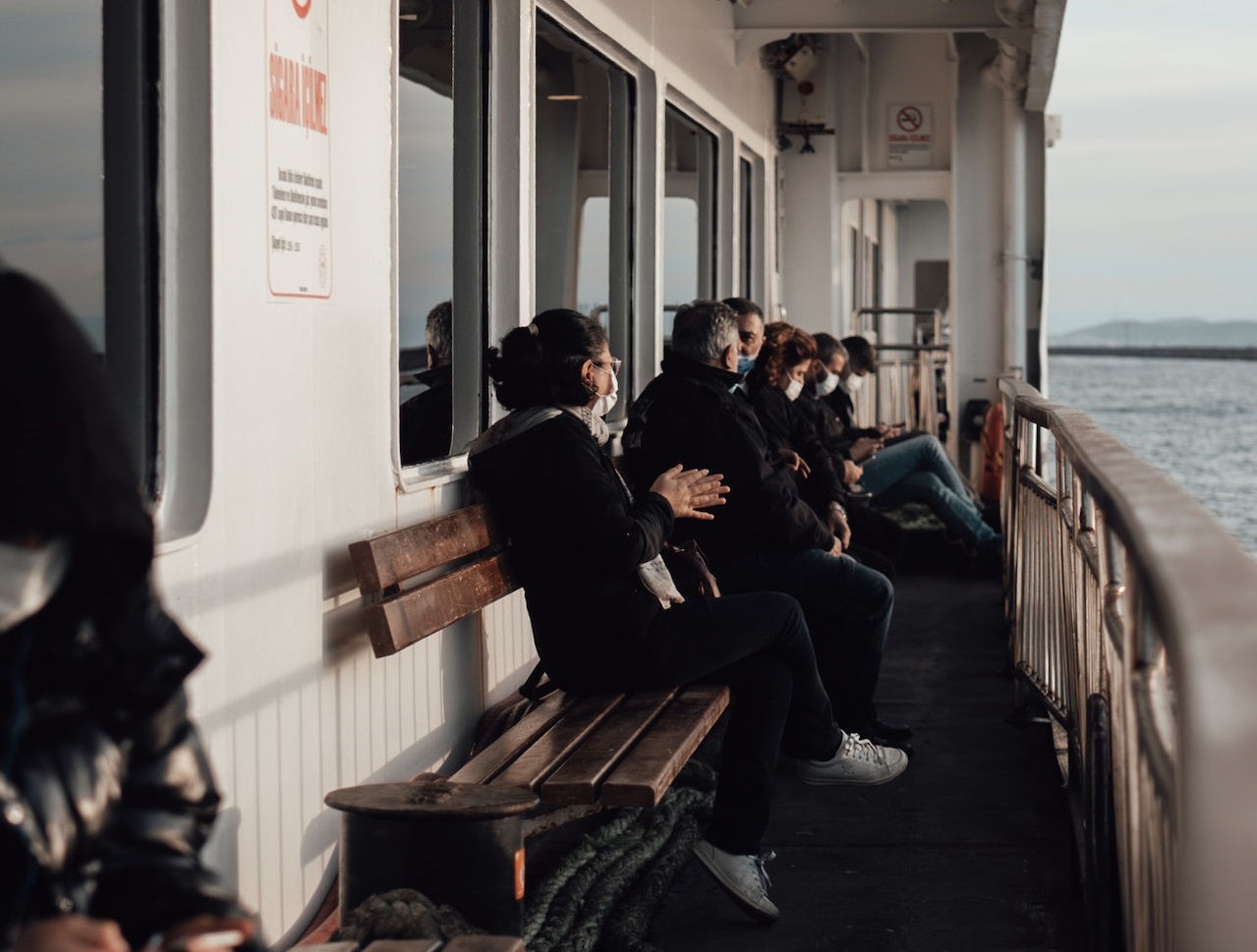 Travelers are resting on benches at trip on ship.