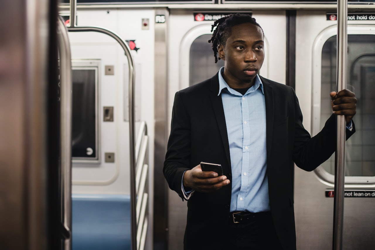 Young man is holding a cell phone and looking inside a train.