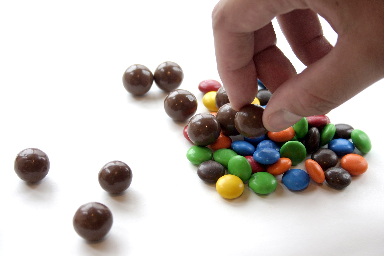 Hand Picking up M&M Candy from the table.