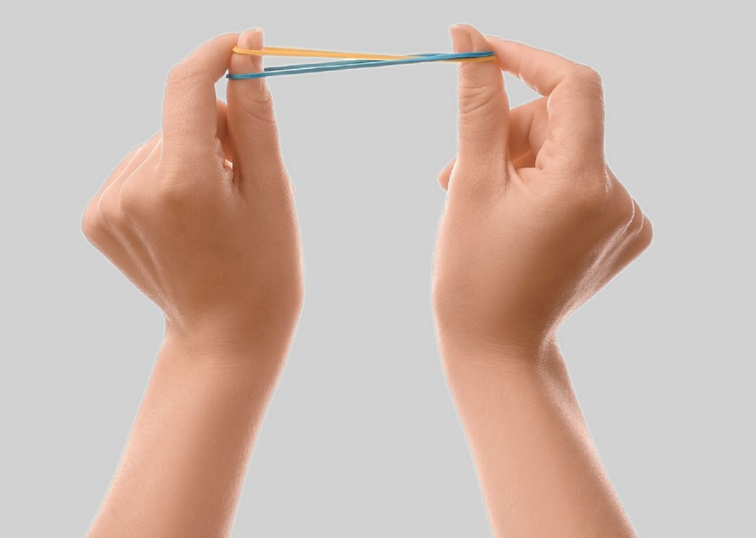 Woman's hands are holding a rubber bands on grey background.