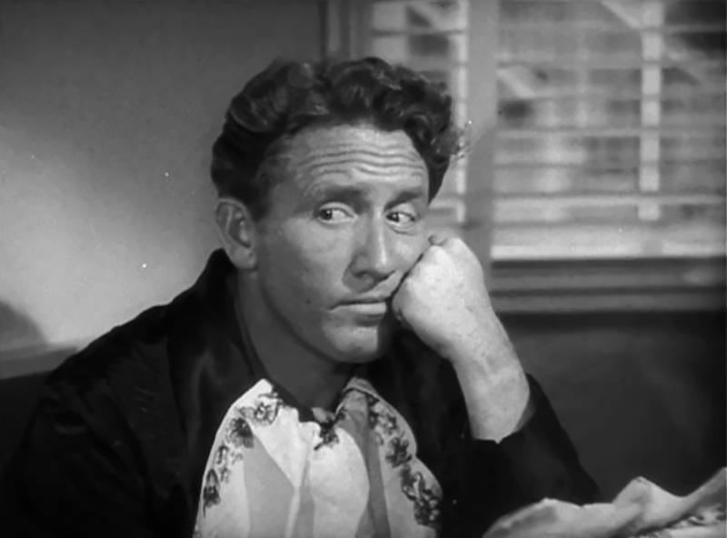 Spencer Tracy sitting at a desk having a meal