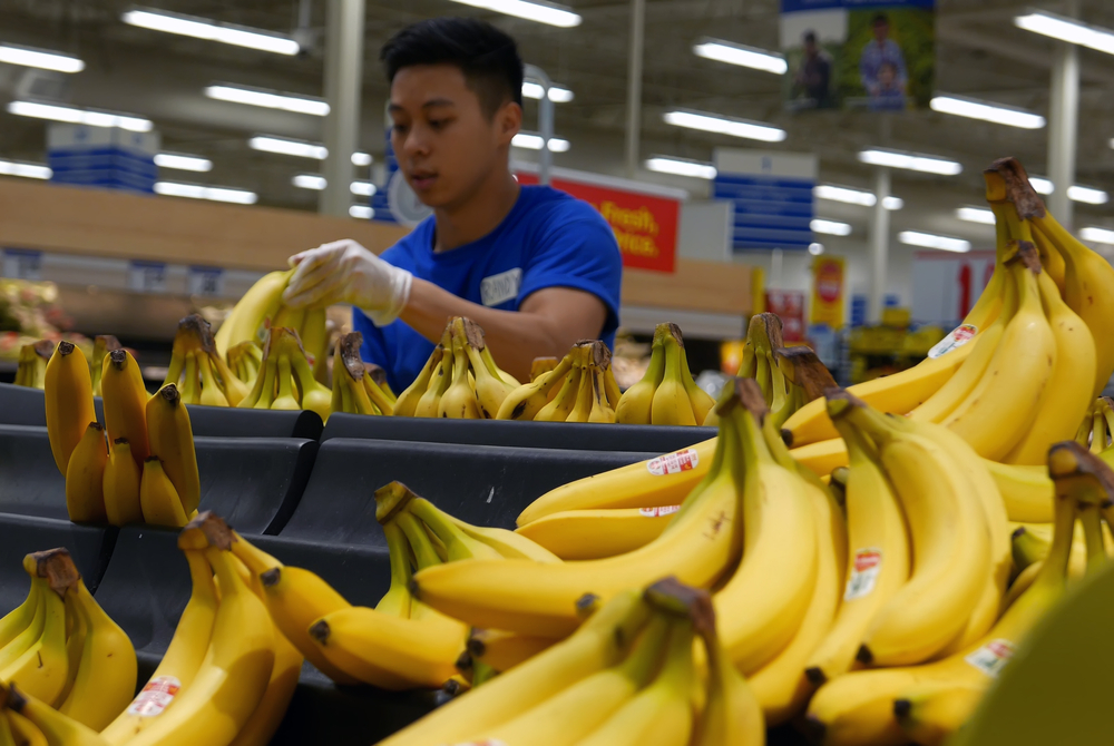 clerk stocking banana on display rack