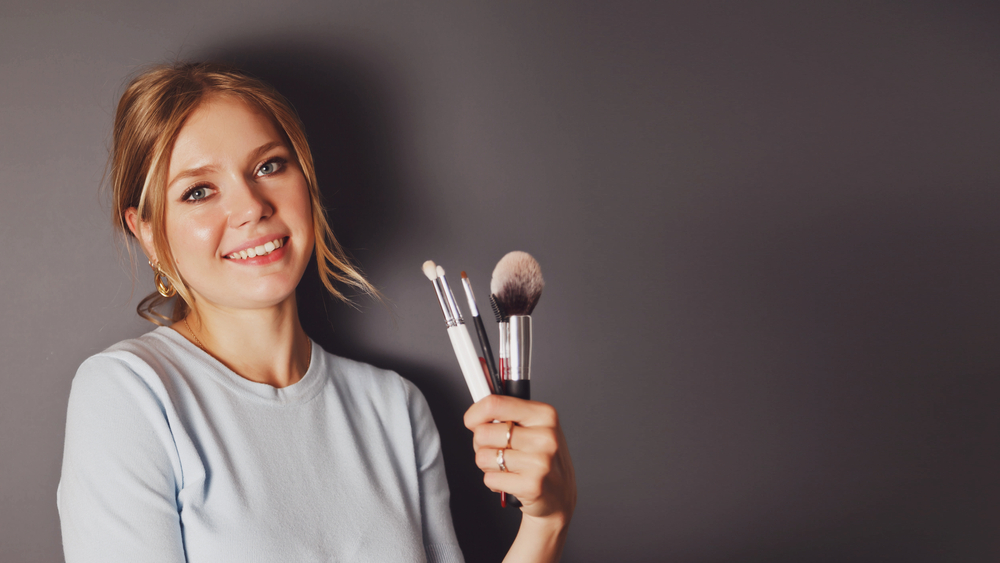 cosmetology teacher in white top and makeup brushes