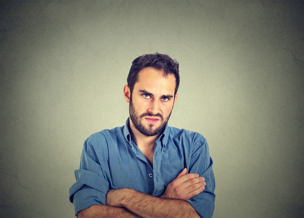 angry young man in blue shirt with crossed arms