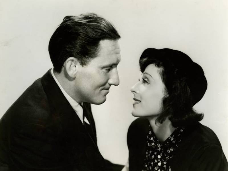 Spencer Tracy and Luise Rainer looking at each other in black jackets