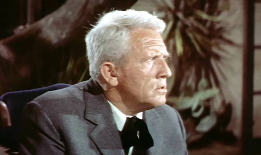 Spencer Tracy in Broken Lance wearing a suit sitting on a chair