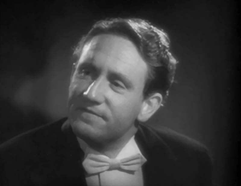 This screenshot shows Spencer Tracy as Dr. Jekyll speaking at a dinner table
