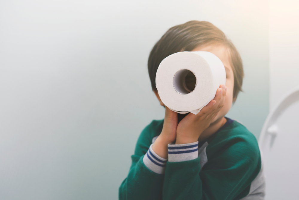 Active boy in green sweater sitting in the toilet