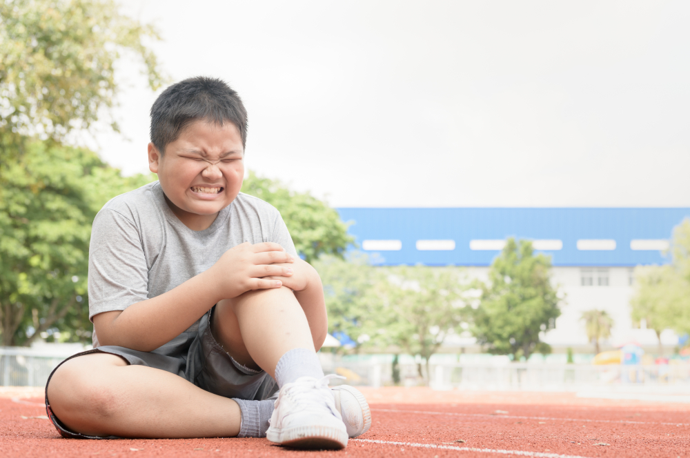Kid athlete suffering form running knee or kneecap injury during outdoor workout