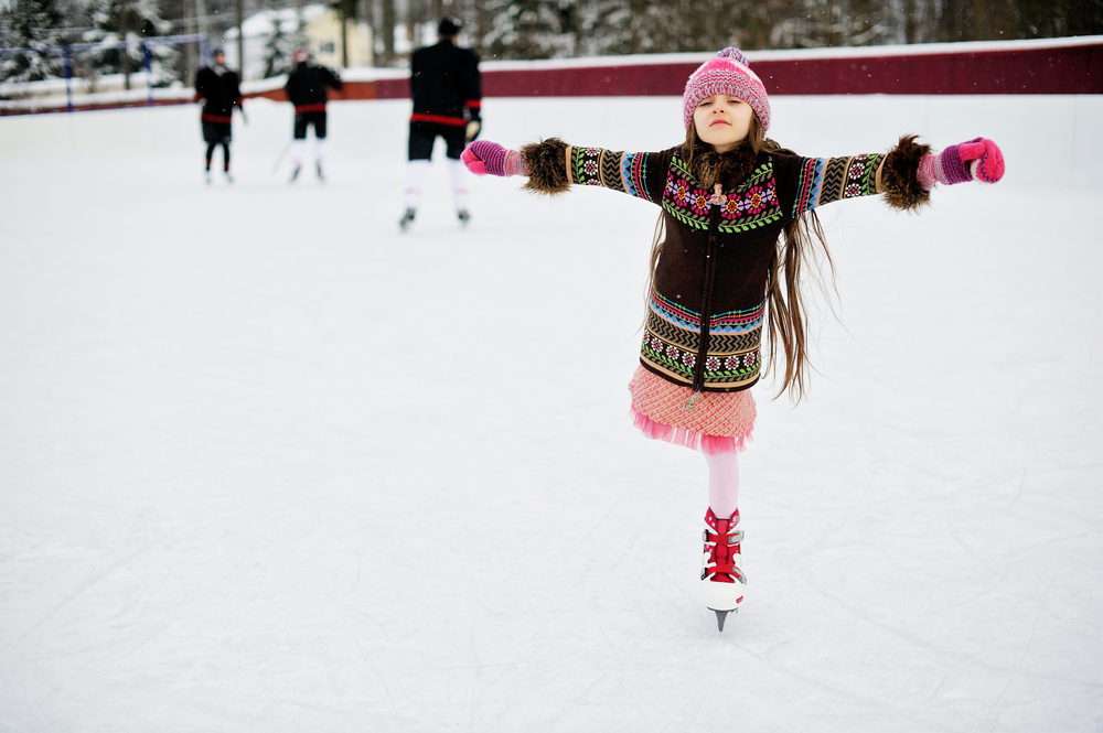 Adorable little girl in winter clothes skating