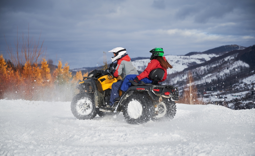 Portrait of young man and woman riding on off-road four-wheeler