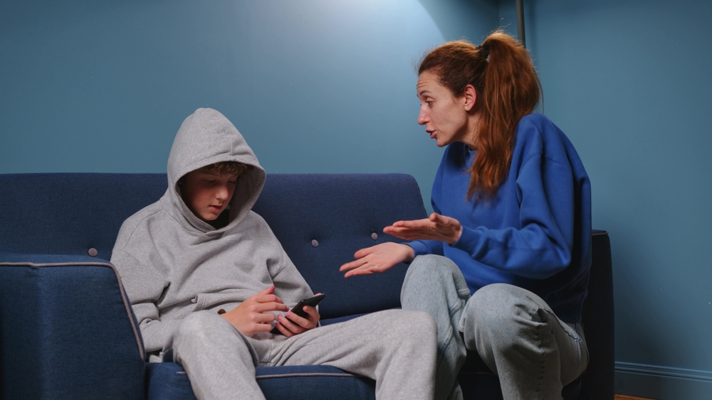 Mother and son sitting on a blue couch arguing about something