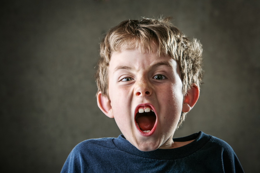 Young Angry boy in blue t-shirt yelling at the camera