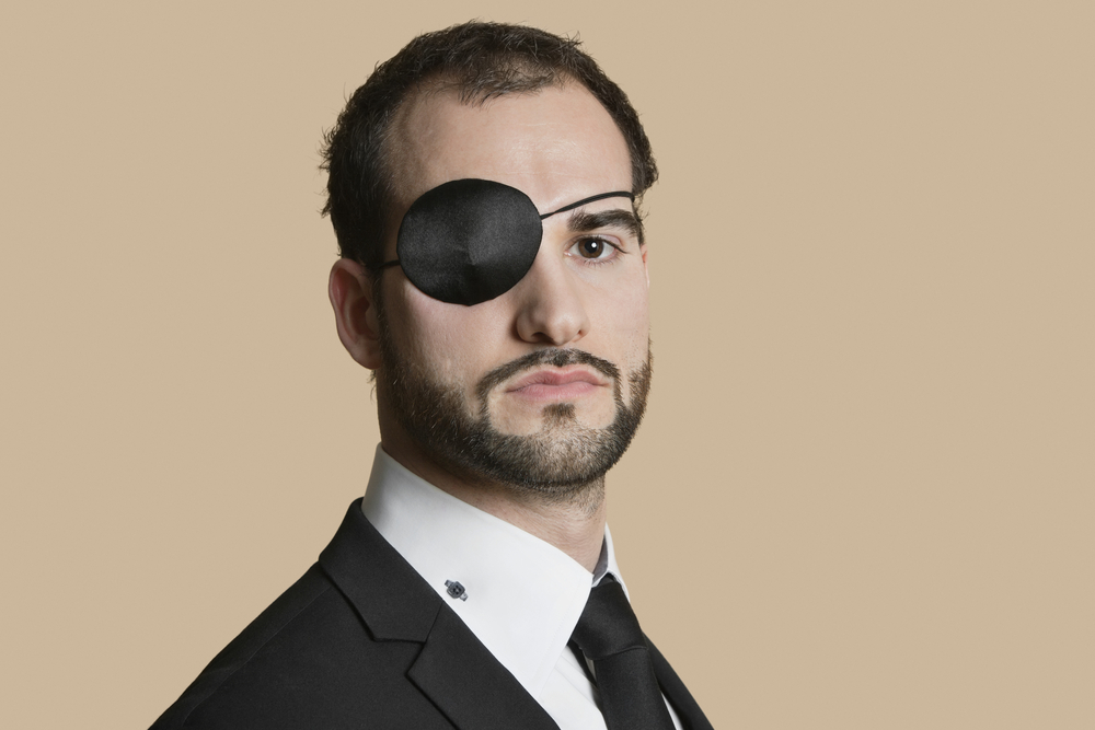 Portrait of a young businessman in suit with eye patch