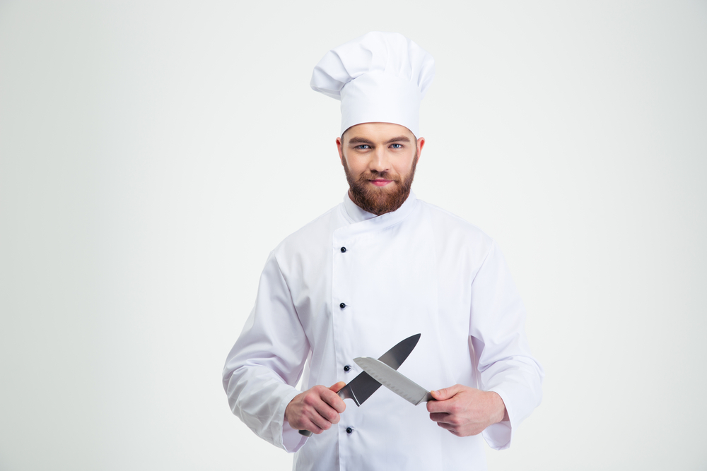 Portrait of a happy male chef cook sharpening a  knife